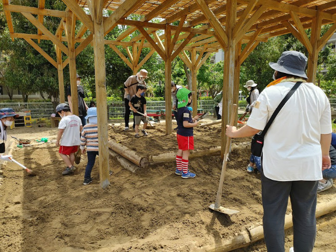 砂場の土を耕し、余った土を土嚢袋に入れる作業です